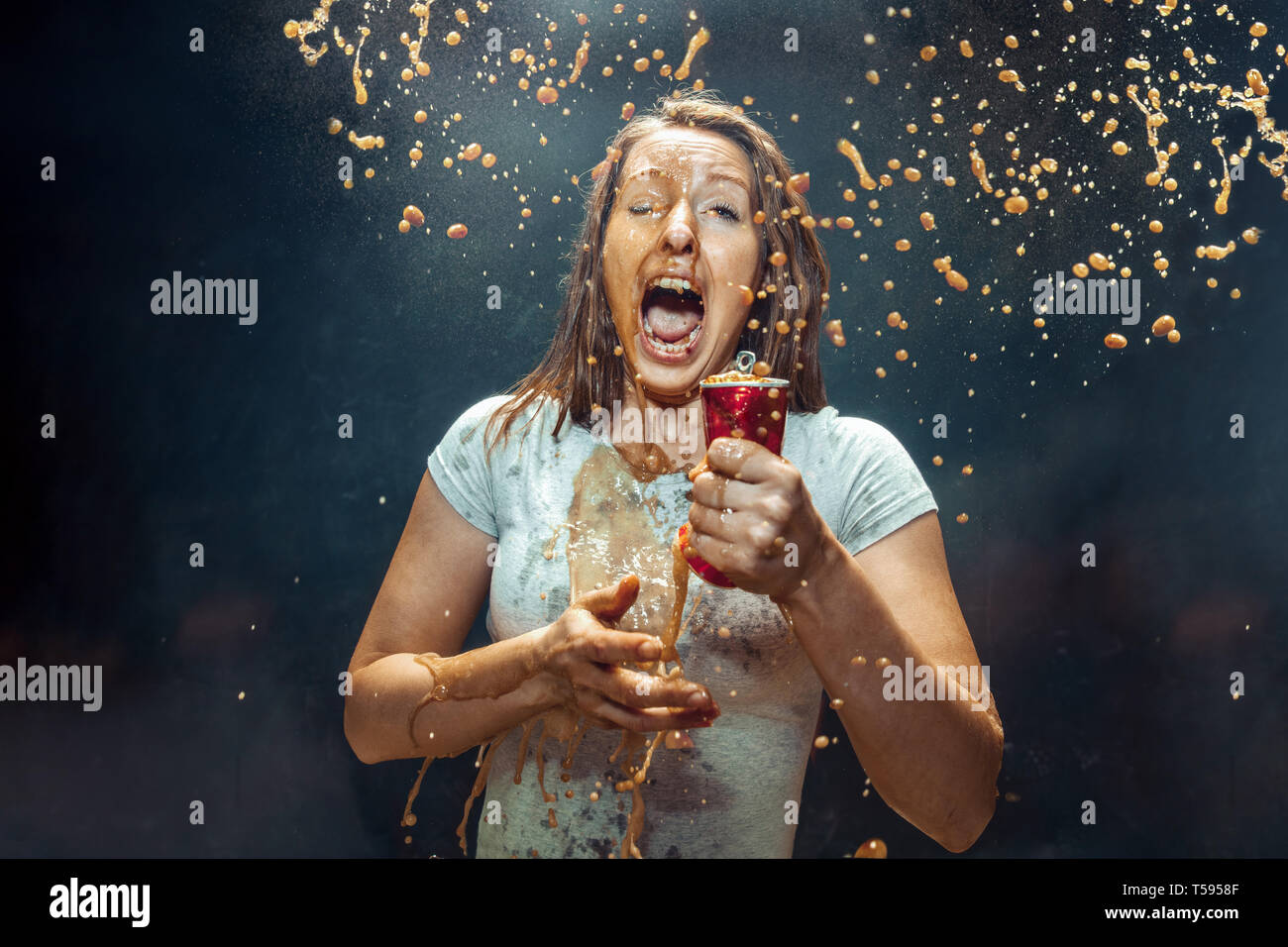 Donna di bere una coca cola in studio. Giovani felici sorridente ragazza caucasica apertura può con cola e godendo di spruzzo. L'immagine pubblicitaria circa drink preferito. Lo stile di vita e le emozioni umane concetto. Foto Stock