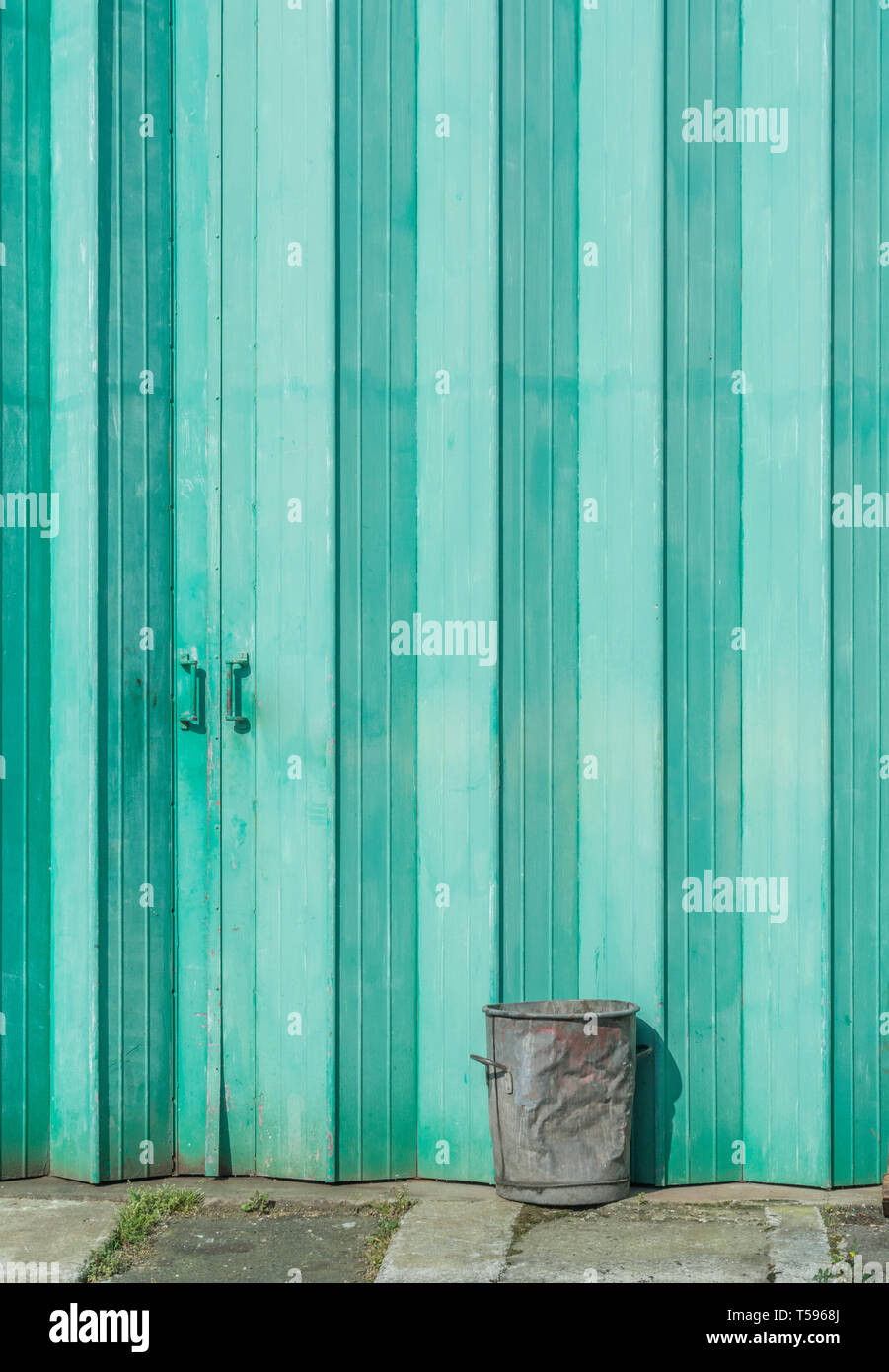 Vecchio bidone di metallo esterno dipinto di verde porte industriali. Industria astratta, metafora isolato, concetto parzializzato o chiudere fuori della discussione. Foto Stock