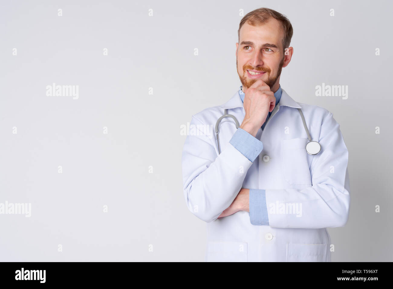 Ritratto di felice giovane uomo barbuto pensiero medico Foto Stock