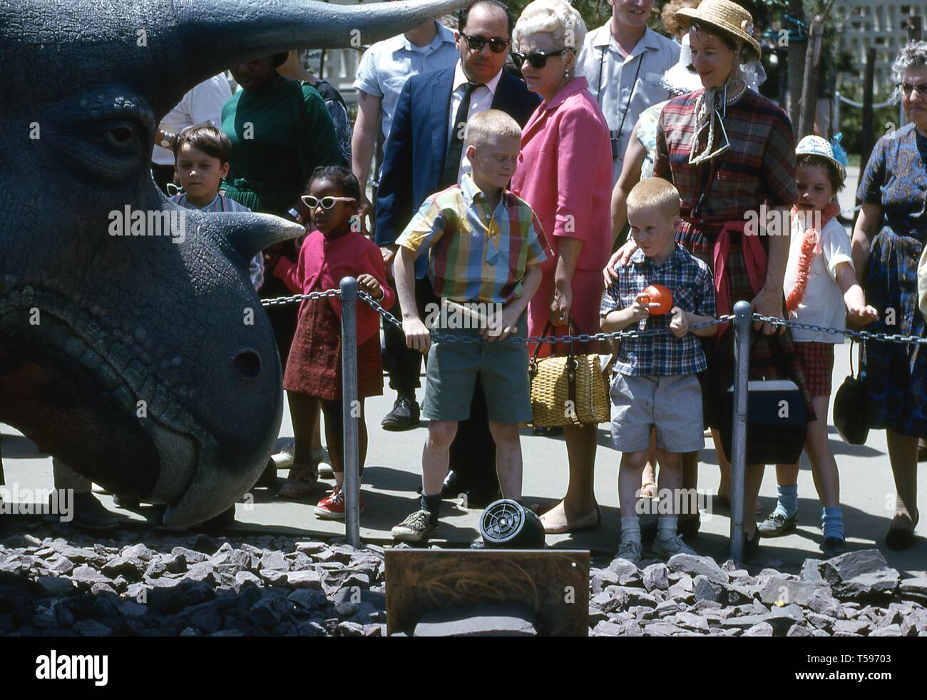 Una folla di persone in una giornata di sole, visualizzazione della testa in fibra di vetro di un Triceratops presso il dinoland presentano, Sinclair Pavilion, 1964 alla fiera mondiale di New York, Flushing Meadows Park, Queens, a New York, maggio, 1964. () Foto Stock