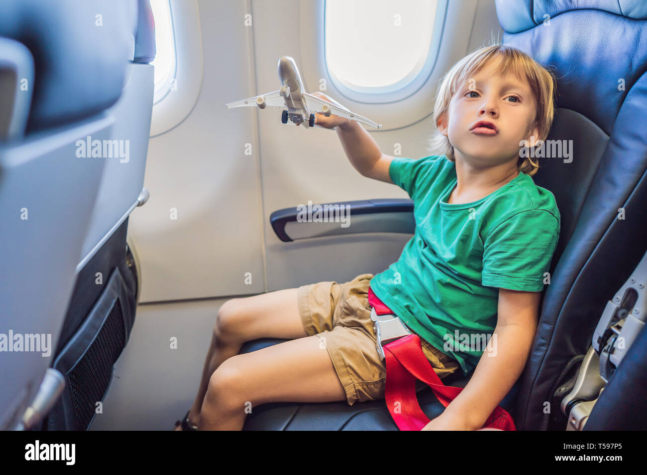 Little Boy gioca con Toy piano nel getto commerciale aereo in vacanza Foto Stock