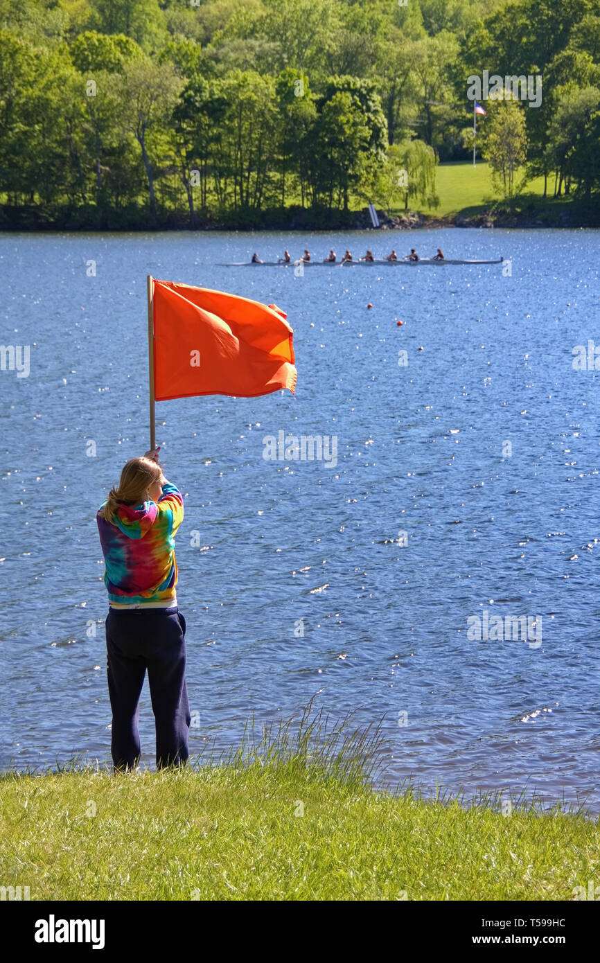 Nuovo Preston, CT, Stati Uniti d'America. Maggio 2010. Una giovane donna di innalzare la bandiera di finitura in un equipaggio di gara di canottaggio. Foto Stock