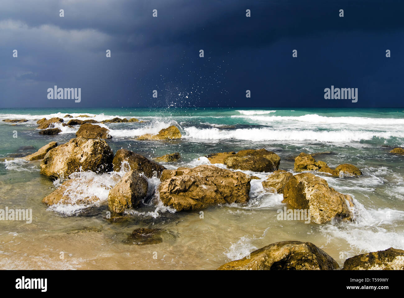 Gli spruzzi di surf, pietre in acqua contro il cielo in tempesta Foto Stock