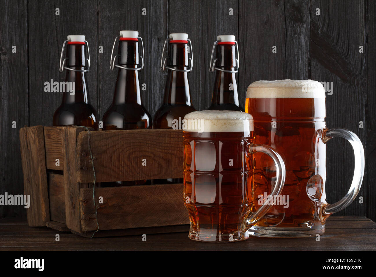 Bicchiere da birra vintage con scatola di legno piena di beeer bottiglie sul tavolo in legno ancora vita Foto Stock