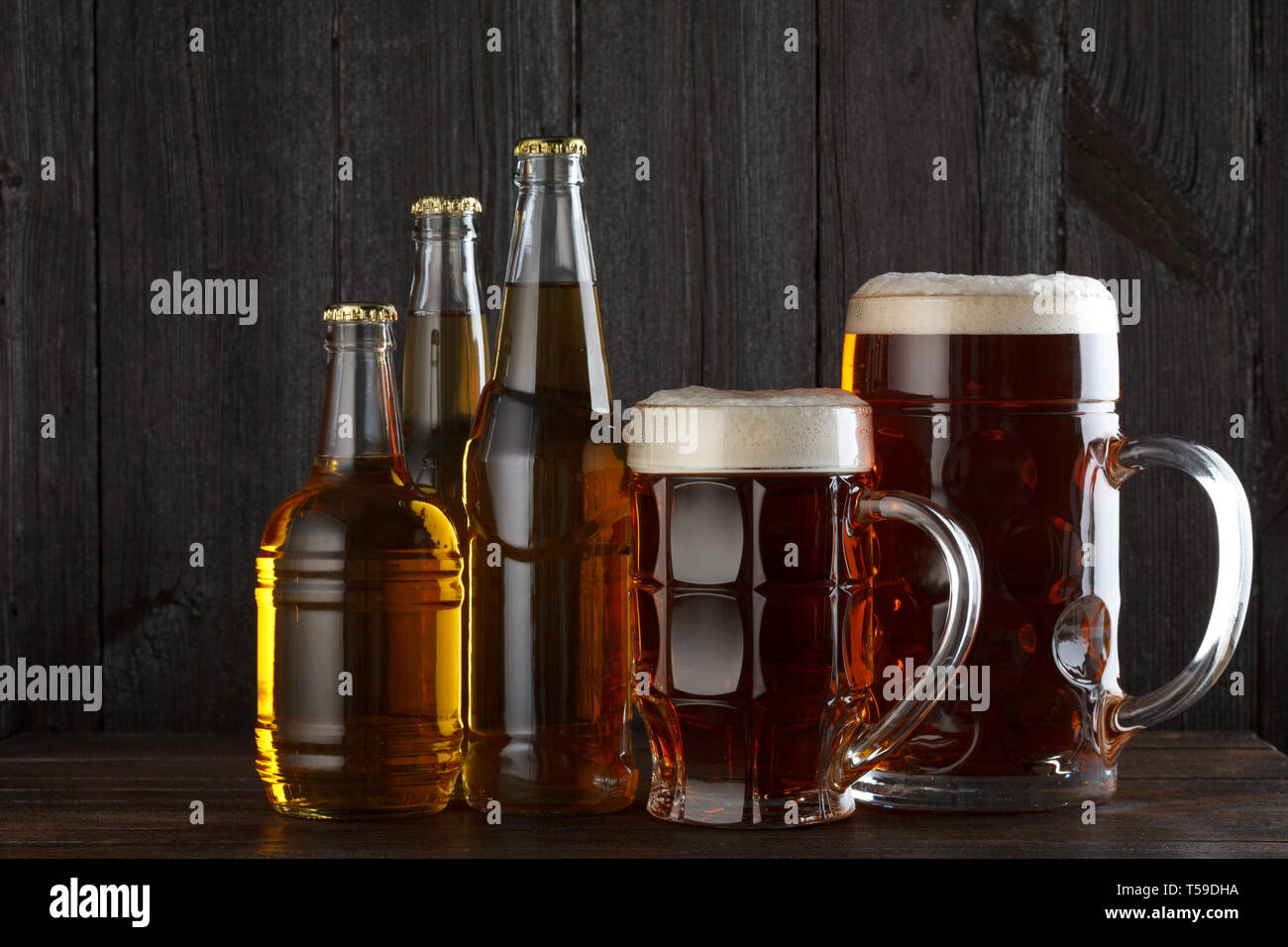 Bicchieri e bottiglie con varietà di birra sul tavolo in legno ancora vita Foto Stock