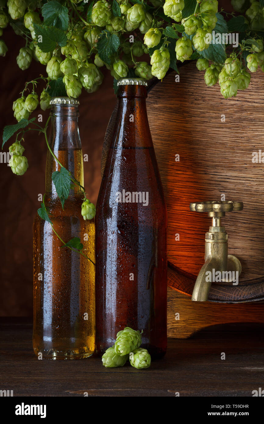 Le bottiglie di birra con il barile di birra e luppolo fresco still-life Foto Stock