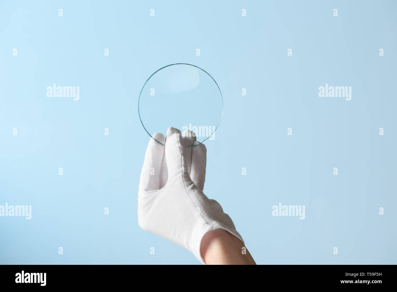 Nuove funzioni di rivestimento di vetro o plastica ricerca, mano nel guanto tenendo premuto cerchio pezzo di materiale trasparente Foto Stock