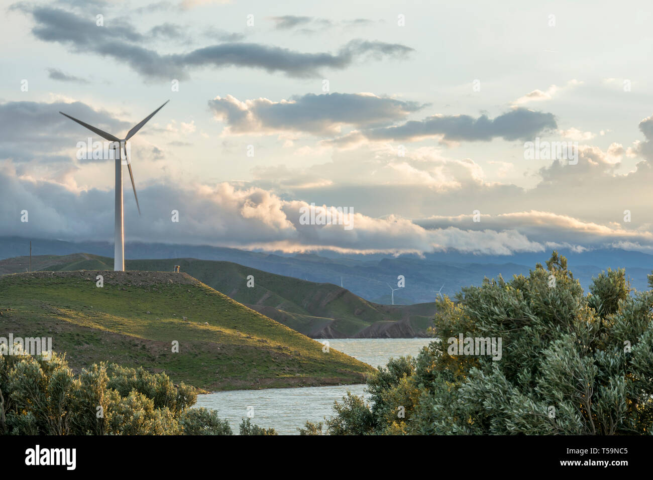 Il potere di vento turbina su di una collina nella parte anteriore del cielo nuvoloso, rispettosi dell'ambiente di produzione di energia elettrica Foto Stock