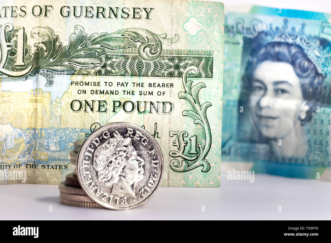 5 pence moneta con l'immagine di Elizabeth II oltre a una sterlina banconota da Guernsey e una offuscata cinque libbre DAL REGNO UNITO Foto Stock