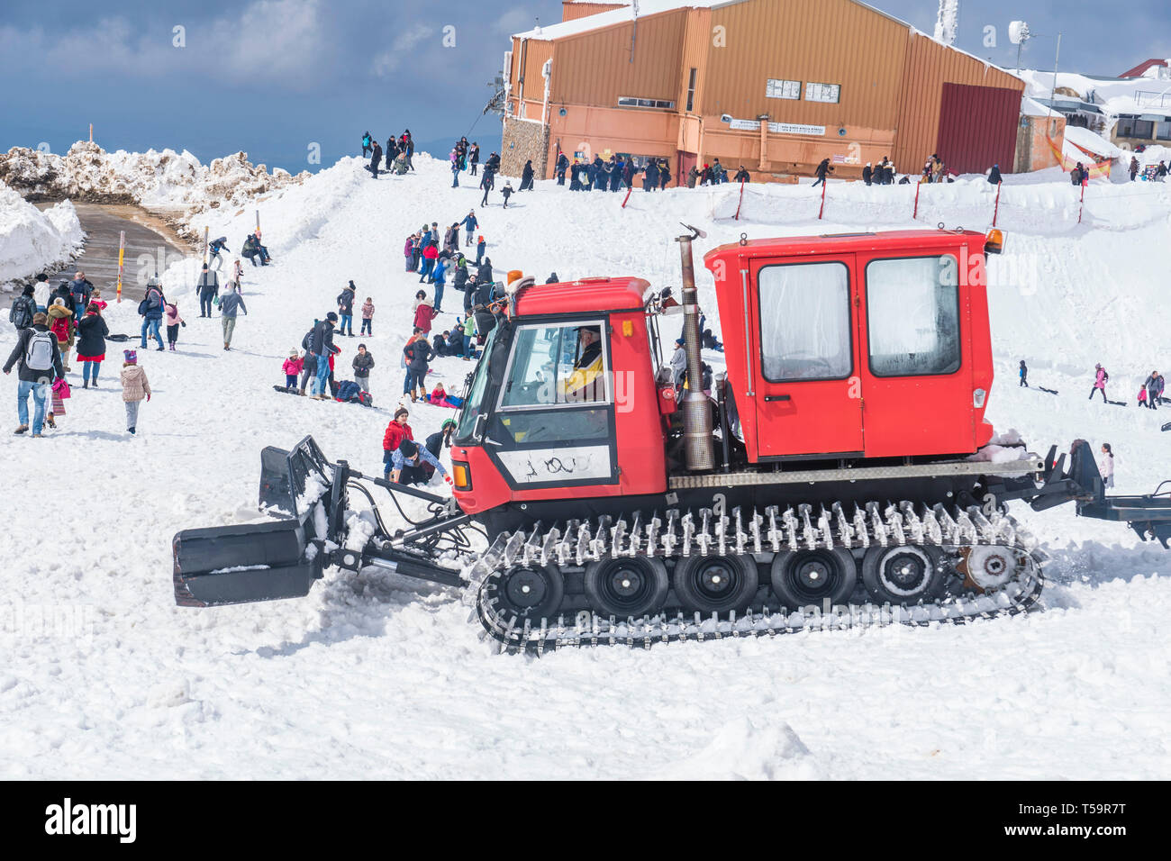 Monte Hermon, Israele. Un gatto delle nevi veicolo cancella la neve vicino a una cabina di sci. Molti visitatori intorno a. Foto Stock