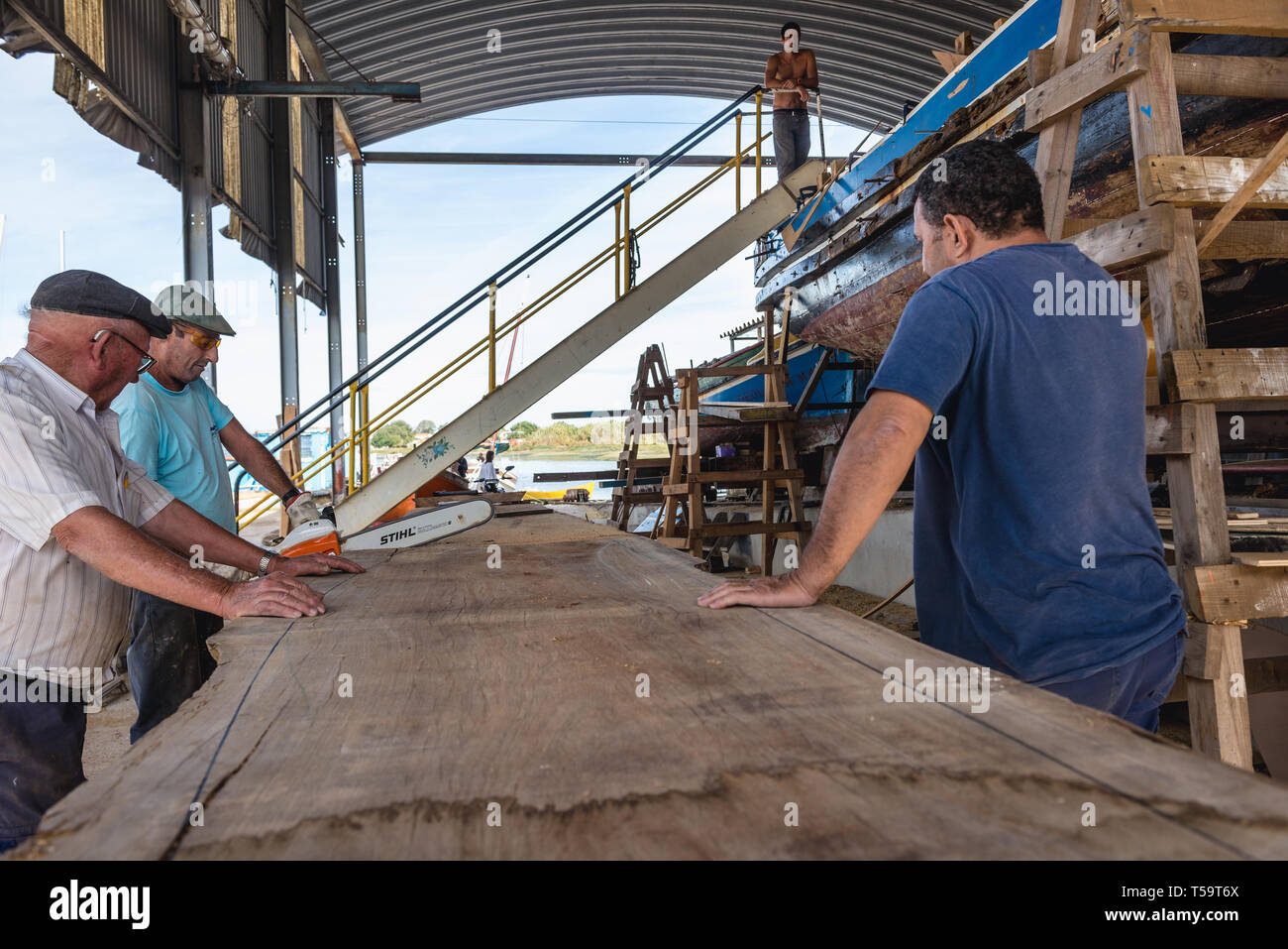 I lavoratori del cantiere navale in cui i tradizionali fiume Tago barche sono costruiti e riparati in Sarilhos Pequenos village a Moita comune, Portogallo Foto Stock