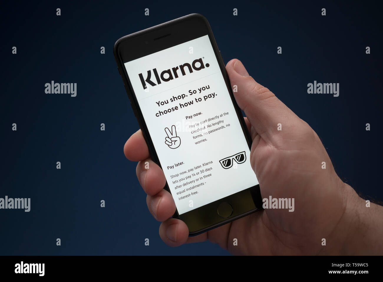 Un uomo guarda al suo iPhone che visualizza il logo Klarna (solo uso editoriale). Foto Stock