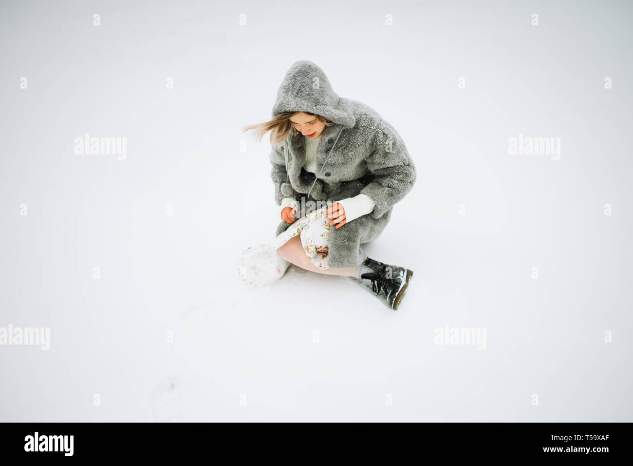 Una donna in pelliccia si siede su un lago innevato in inverno Foto Stock