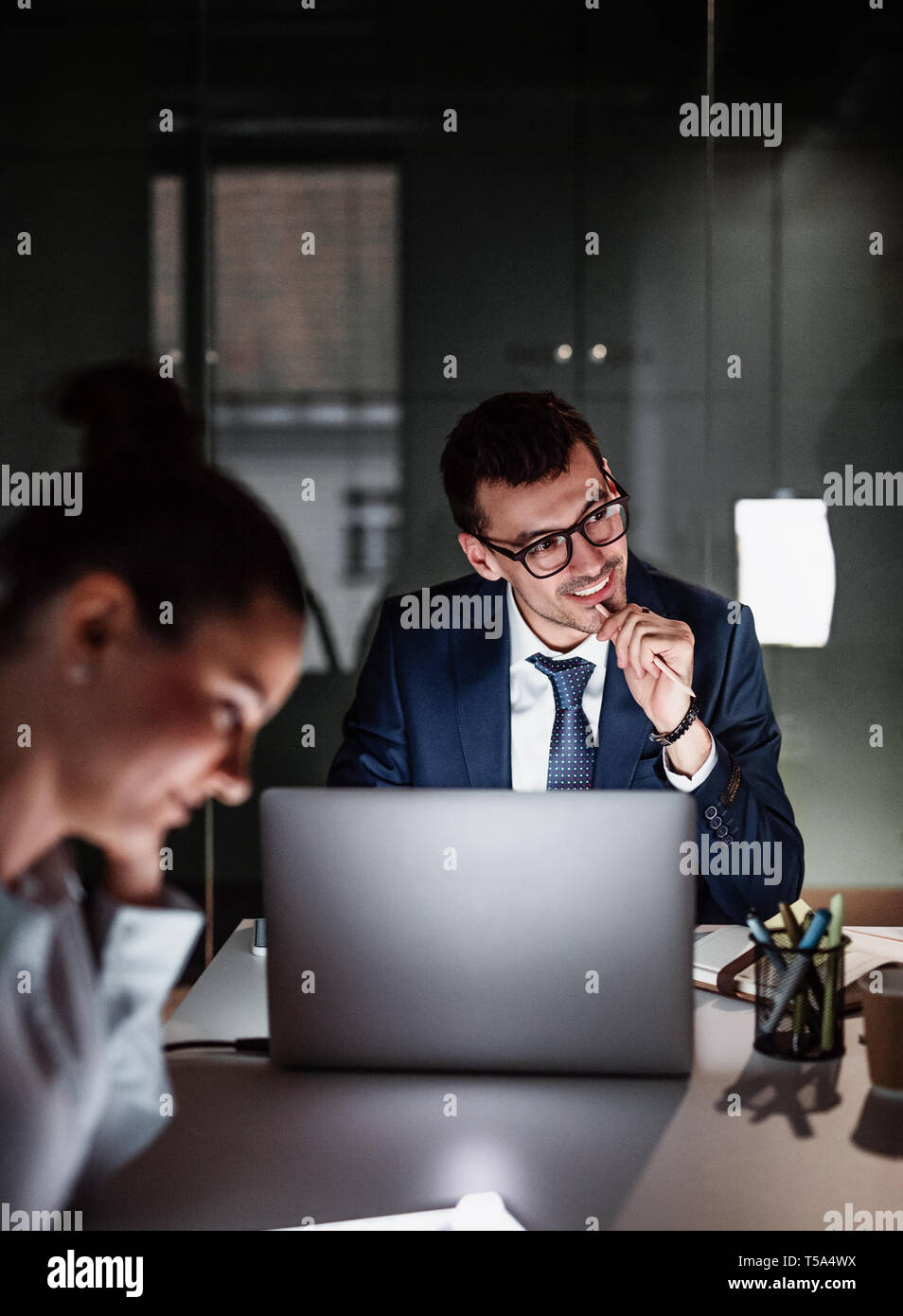 Un ritratto di felice giovane imprenditore con computer in un ufficio,funzionante. Foto Stock