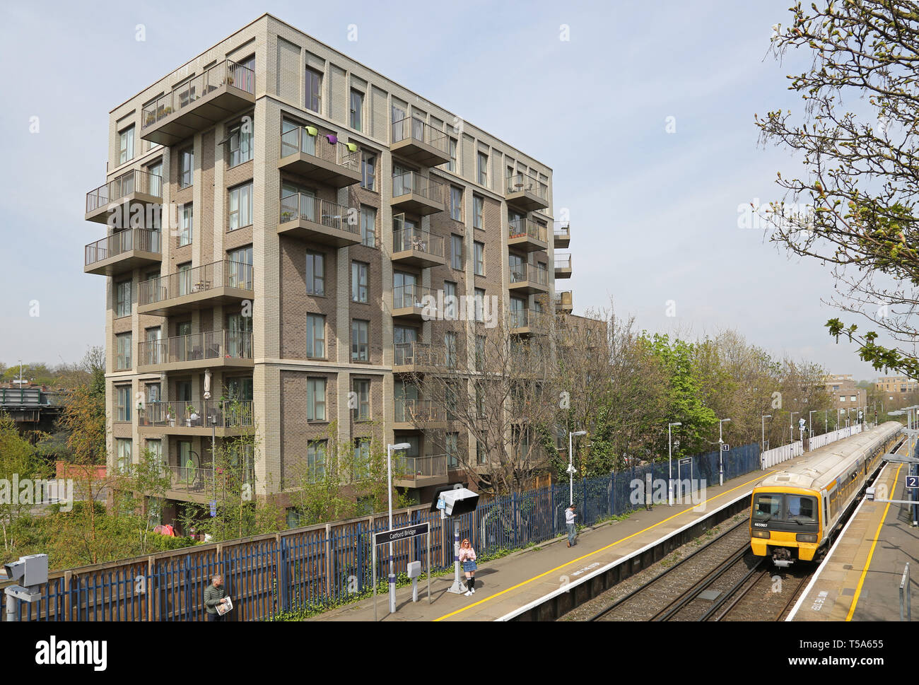 Un treno arriva a Catford Stazione del Ponte, a sud di Londra, Regno Unito. Appartamento nuovo blocco al di là - uno dei molti costruita di recente nella Catford. Foto Stock