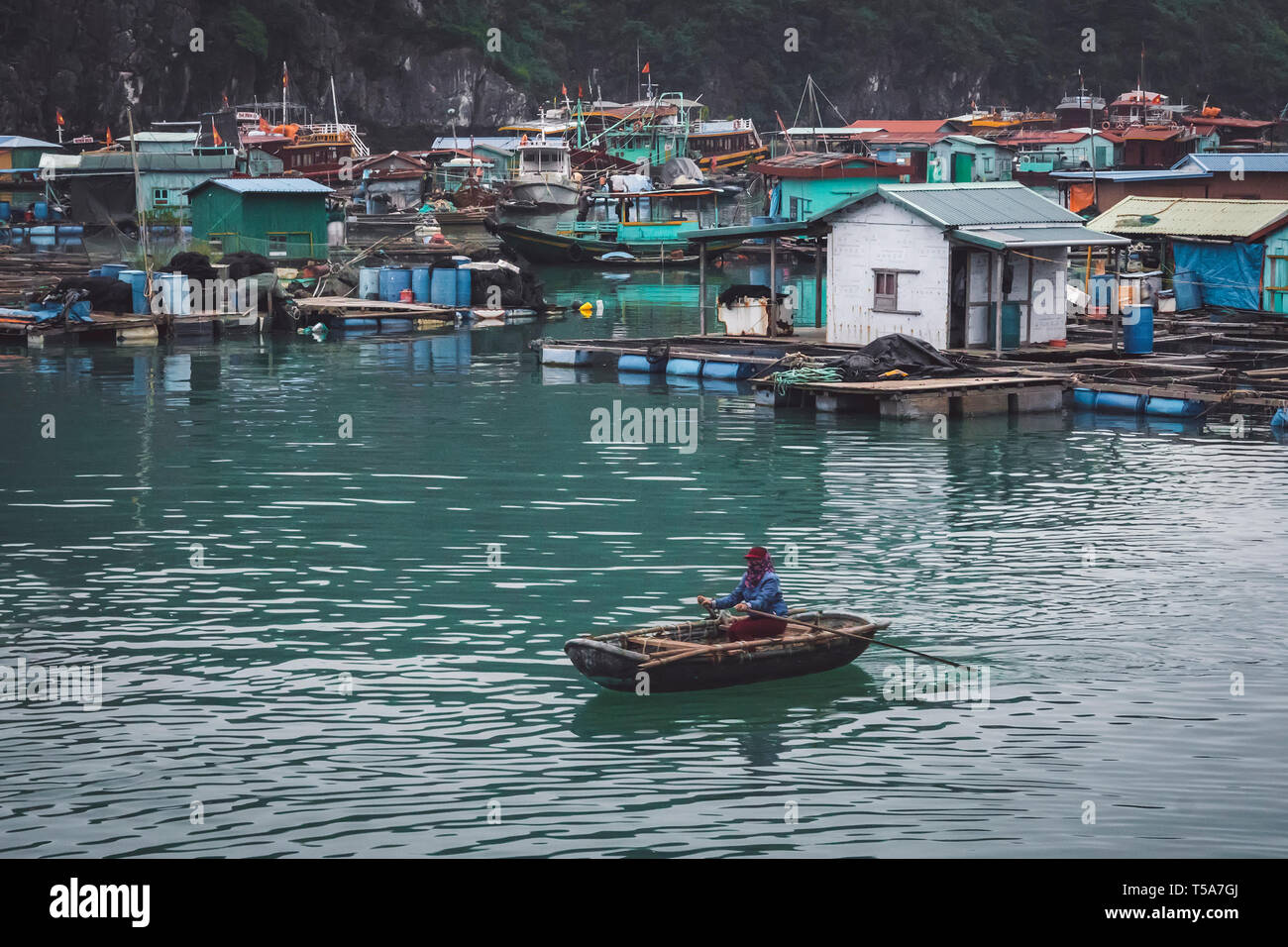 Flottante fattoria di pesce nella baia di Ha Long in Vietnam. Il vietnamita donna su un allevamento ittico. produzione di pesce e frutti di mare in mare. poveri e indigenti fisherwoman, f Foto Stock