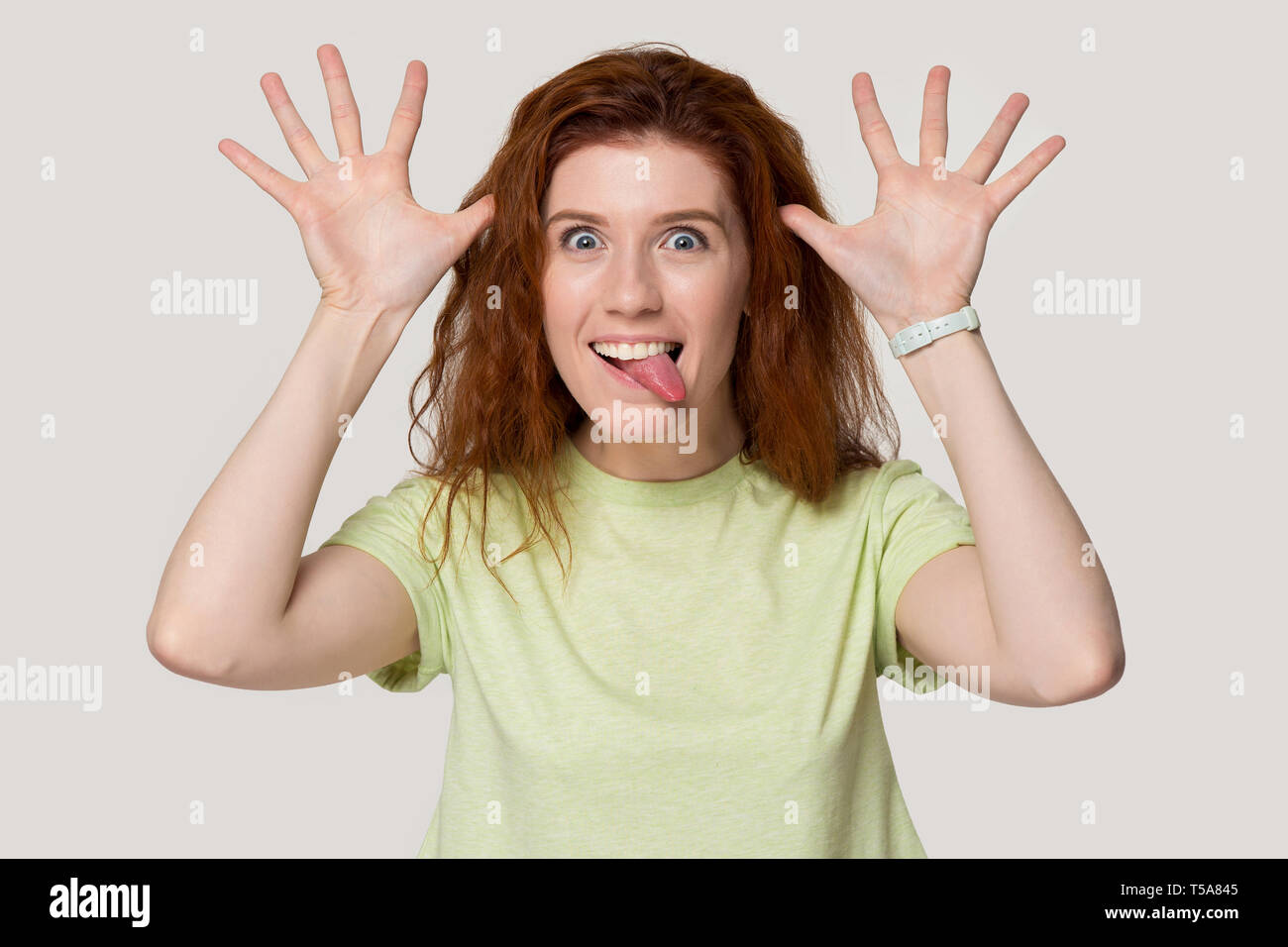 Sorridente ragazza redhead giocare stolte mostrando facce buffe Foto Stock