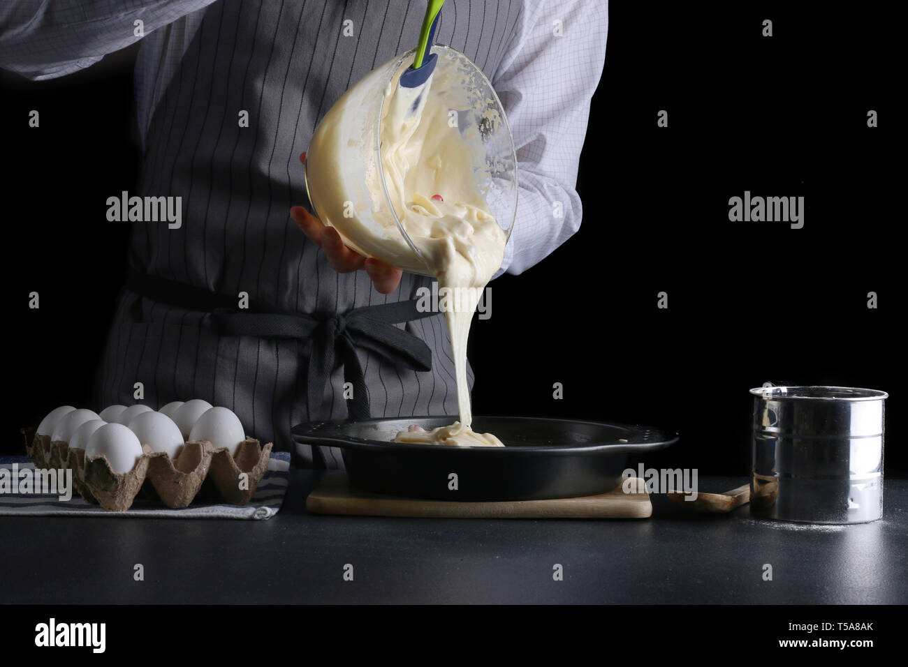 Torta di versare lâ impasto in una teglia da forno. man tenere ciotola e  versare la pastella Foto stock - Alamy