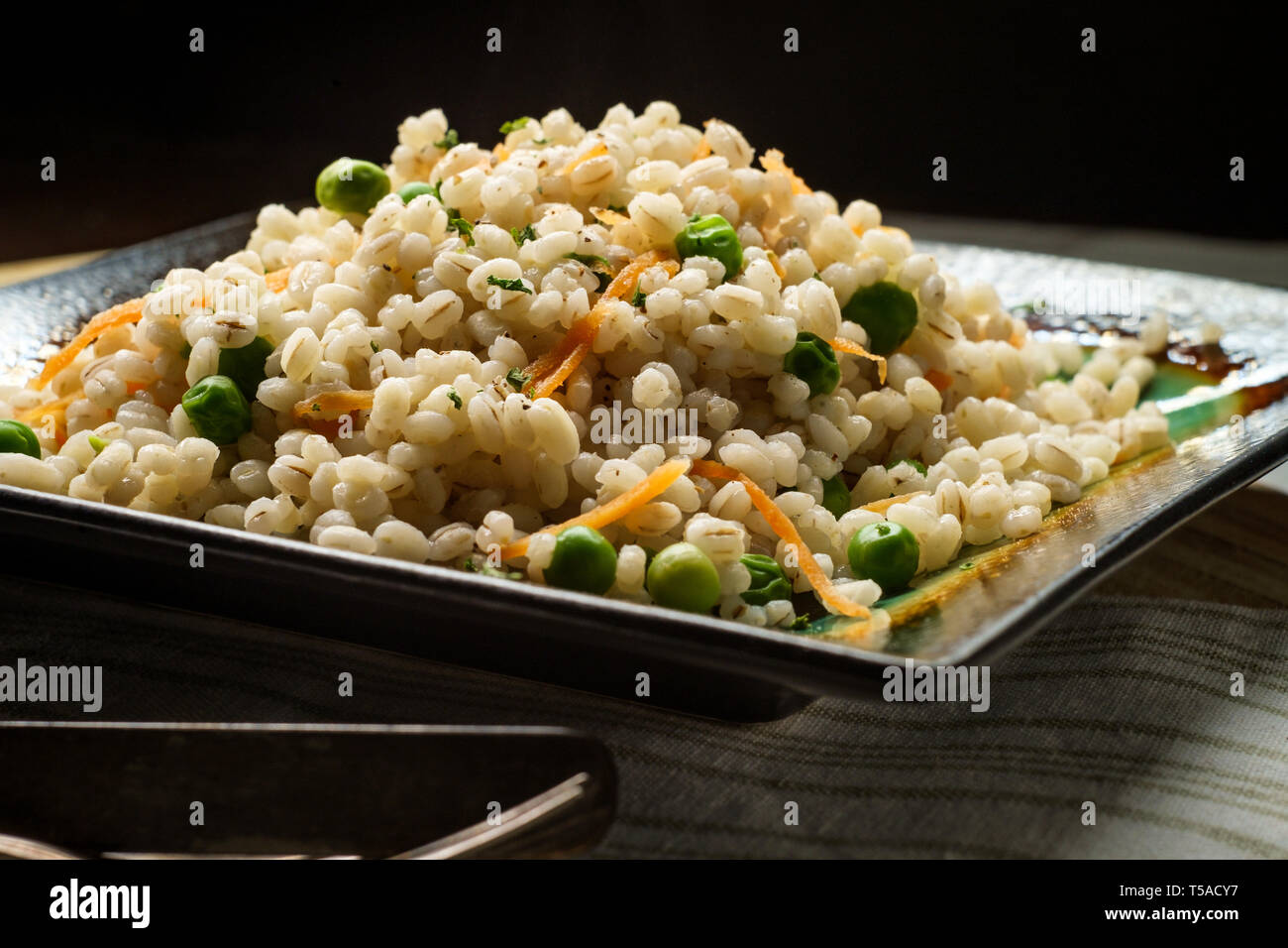 Cuocere orzo perlato porridge con piselli verdi e carote grattugiate Foto Stock