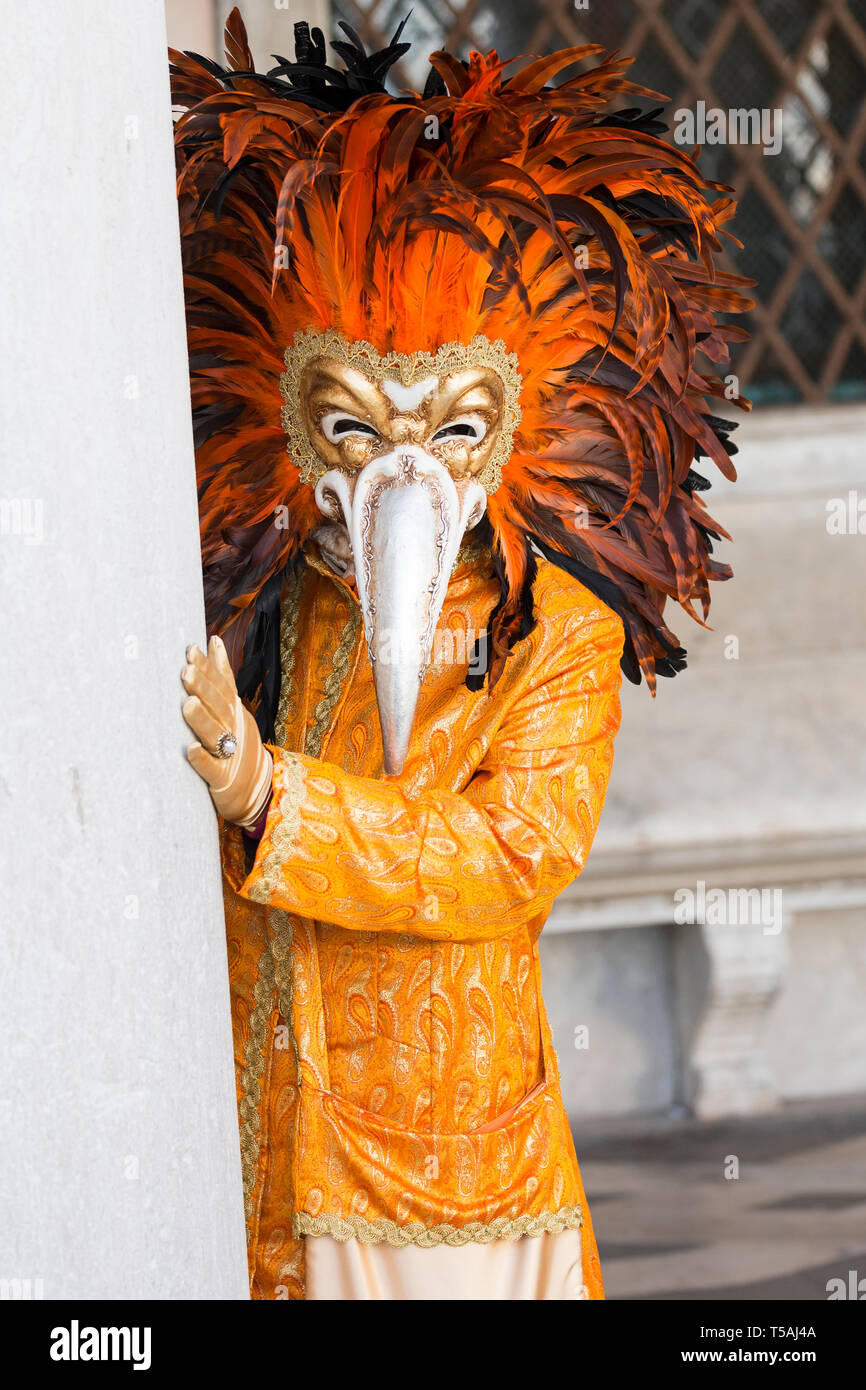 Persona che indossa veneziana tradizionale lungo naso a becco e maschera di  colore arancio brillante, costume di carnevale di Venezia, Italia Foto  stock - Alamy