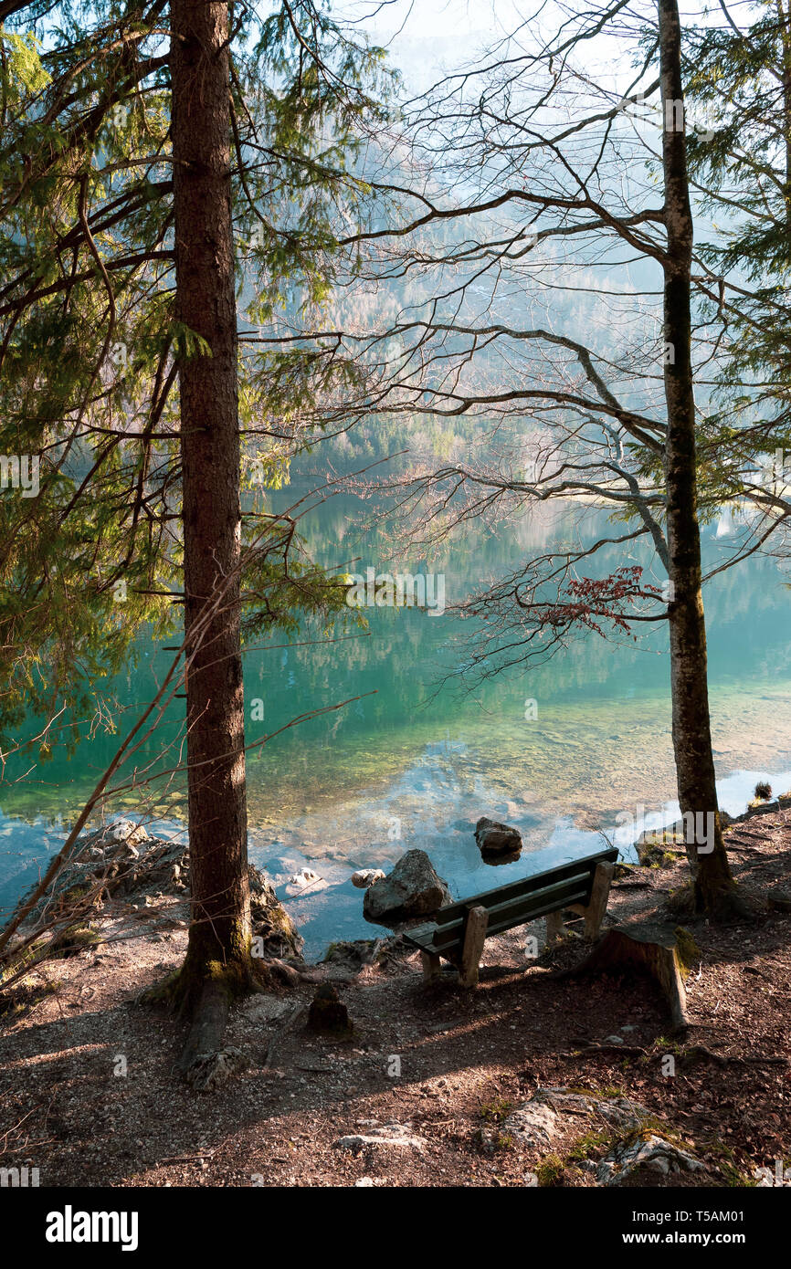 Svuotare panca in legno sulla riva della Vorderer Langbathsee vicino Ebensee, OÖ, Austria, con il grande paesaggio riflettendo sull'acqua cristallina Foto Stock