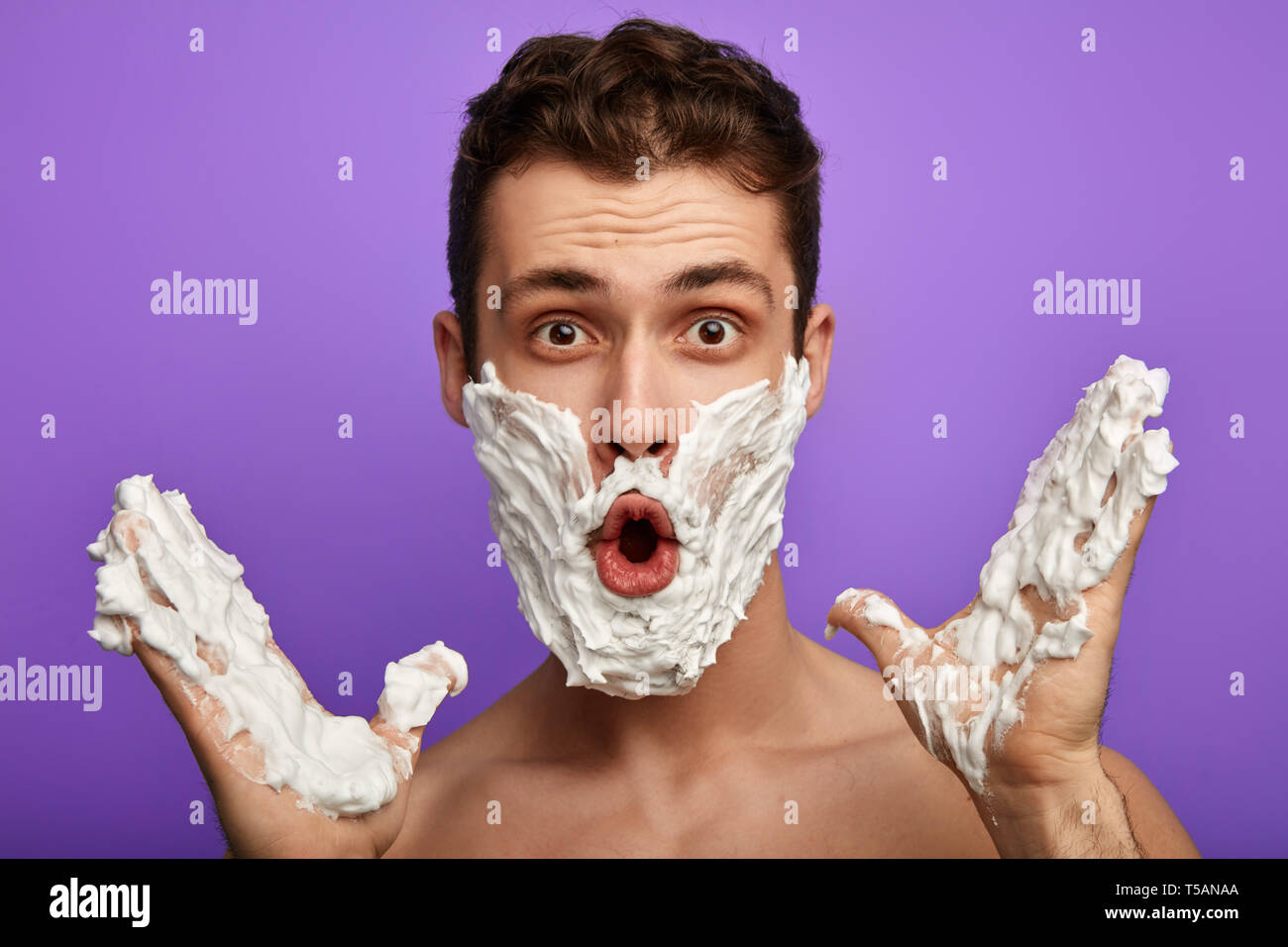 Emotivo uomo di talento cantando canzoni durante la rasatura la sua barba. close up foto. isolato in sfondo blu.incredulità concetto. Omg Foto Stock