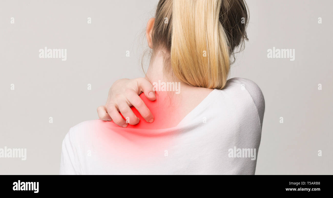 Donna di graffiare il suo prurito al collo e alla spalla Foto stock - Alamy