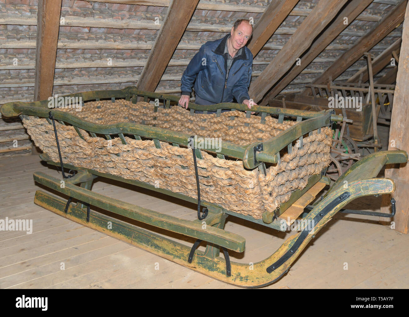 Archiviato - 10 aprile 2019, il Land Brandeburgo, Groß Schönebeck: Jürgen Bohm, collezionista di carrelli e hobby farmer, sorge dietro un cestello sled dal 1920 circa. Più di 100 carrelli, slittini e handcars stand nelle stalle di Jürgen Bohm. (A 'sul pullman box con Jürgen Bohm') foto: Patrick Pleul/ZB Foto Stock