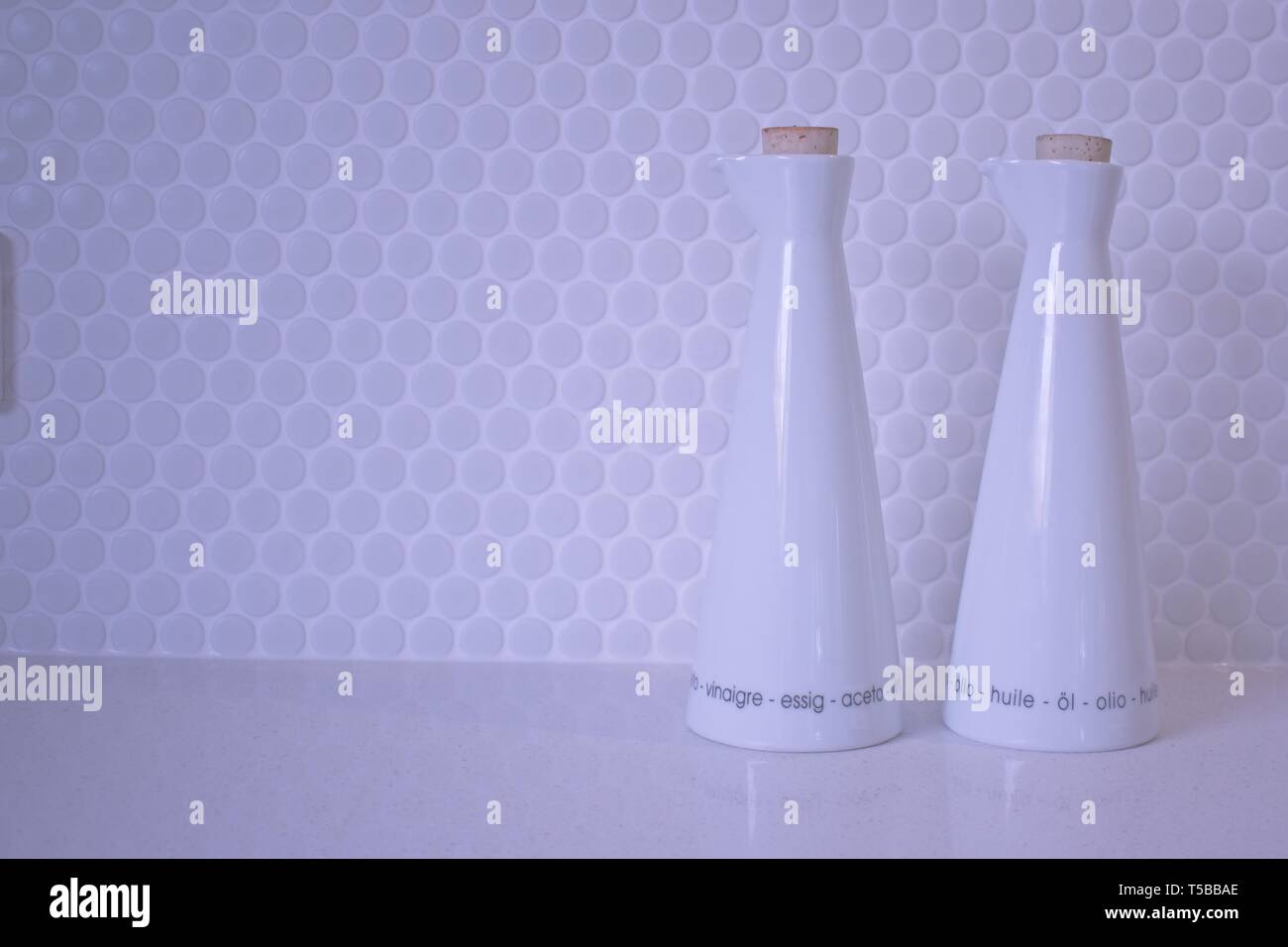 Olio e aceto bottiglie su una bianca parete piastrellata Foto Stock