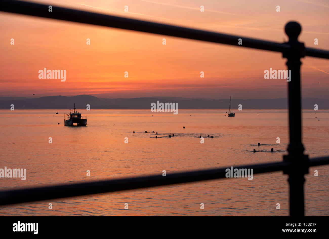 Un gruppo di mattina presto nuotatori prendere il mare durante il weekend di Pasqua Alba vicino al piccolo villaggio di Mumbles vicino a Swansea come questa mattina la Foto Stock