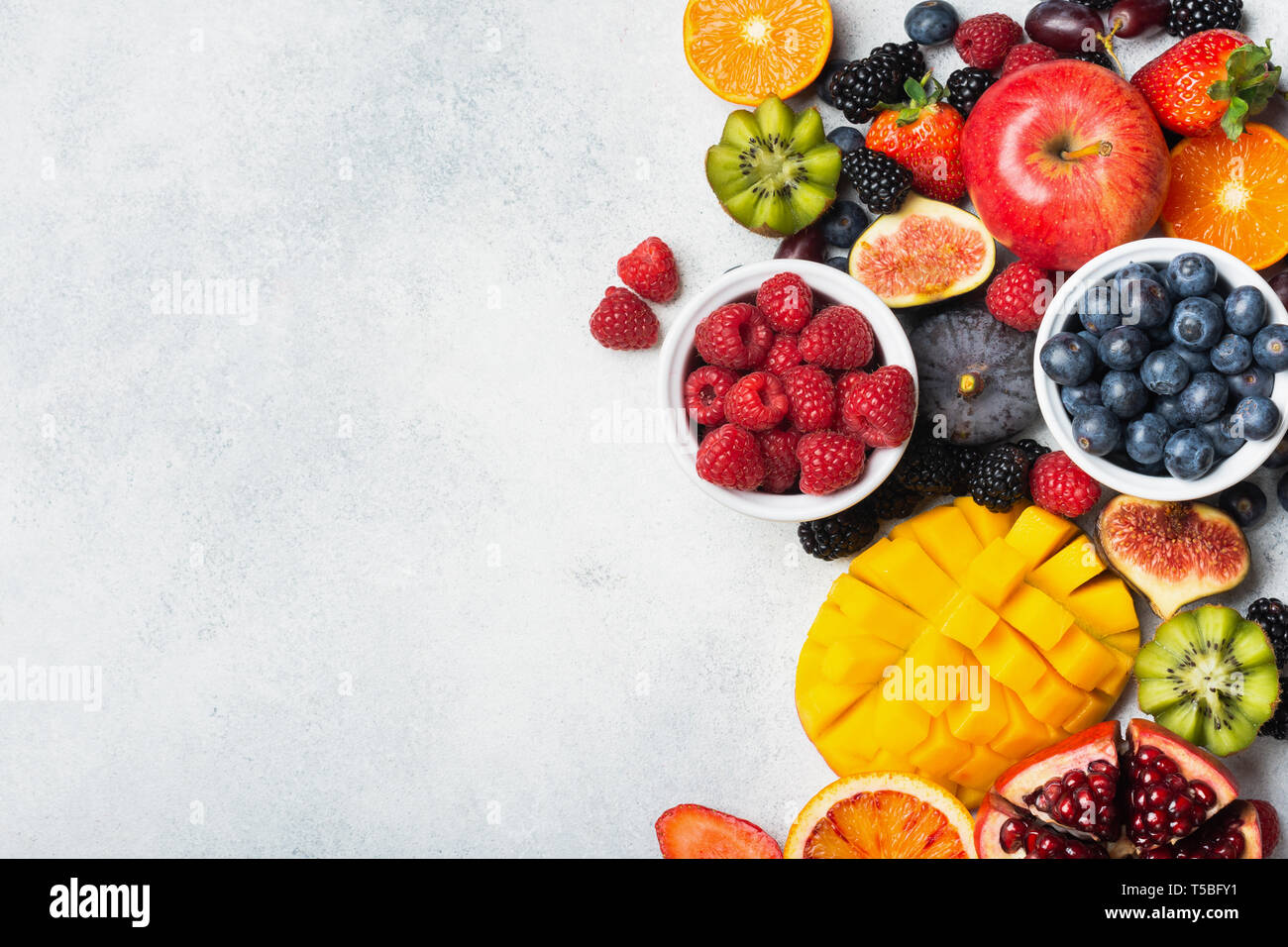 Raw sani frutti arcobaleno, Manghi Papaie Fragole arance passione frutti in bacche di forma ovale piatto da cucina di luce superiore, vista dall'alto, copia di spazio, il fuoco selettivo Foto Stock