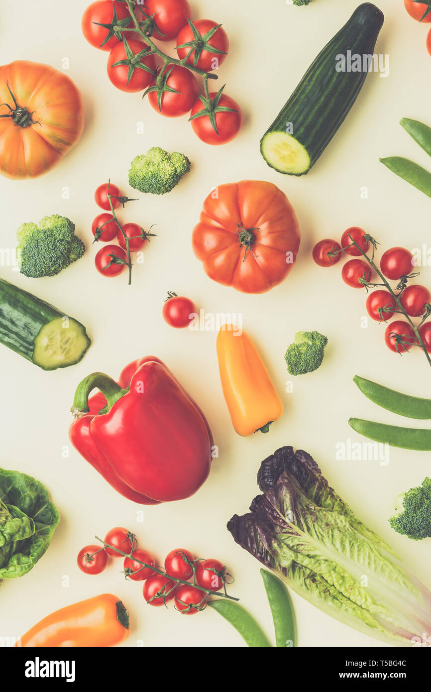 Freschi ingredienti grezzi per insalata Pomodori Cetrioli insalata di avocado pepe cipollina broccoli piselli sulla tavola di crema, vista dall'alto, tonica, il fuoco selettivo Foto Stock