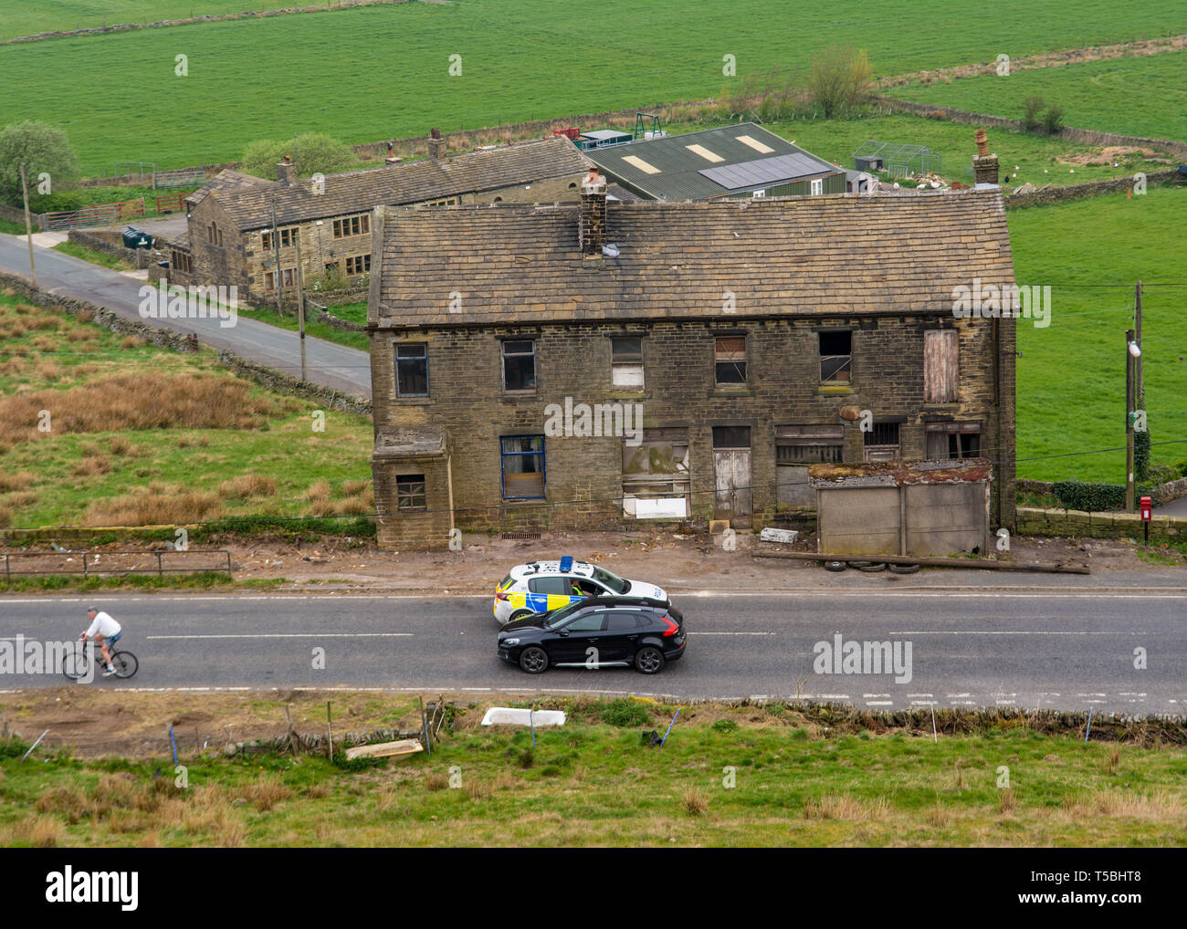 Marsden, nello Yorkshire, 23 Aprile 19. Una macchina della polizia arresta un civile dalla guida passato la strada chiusa segno, come un ciclista passa verso il selvaggio degli incendi. Foto Stock