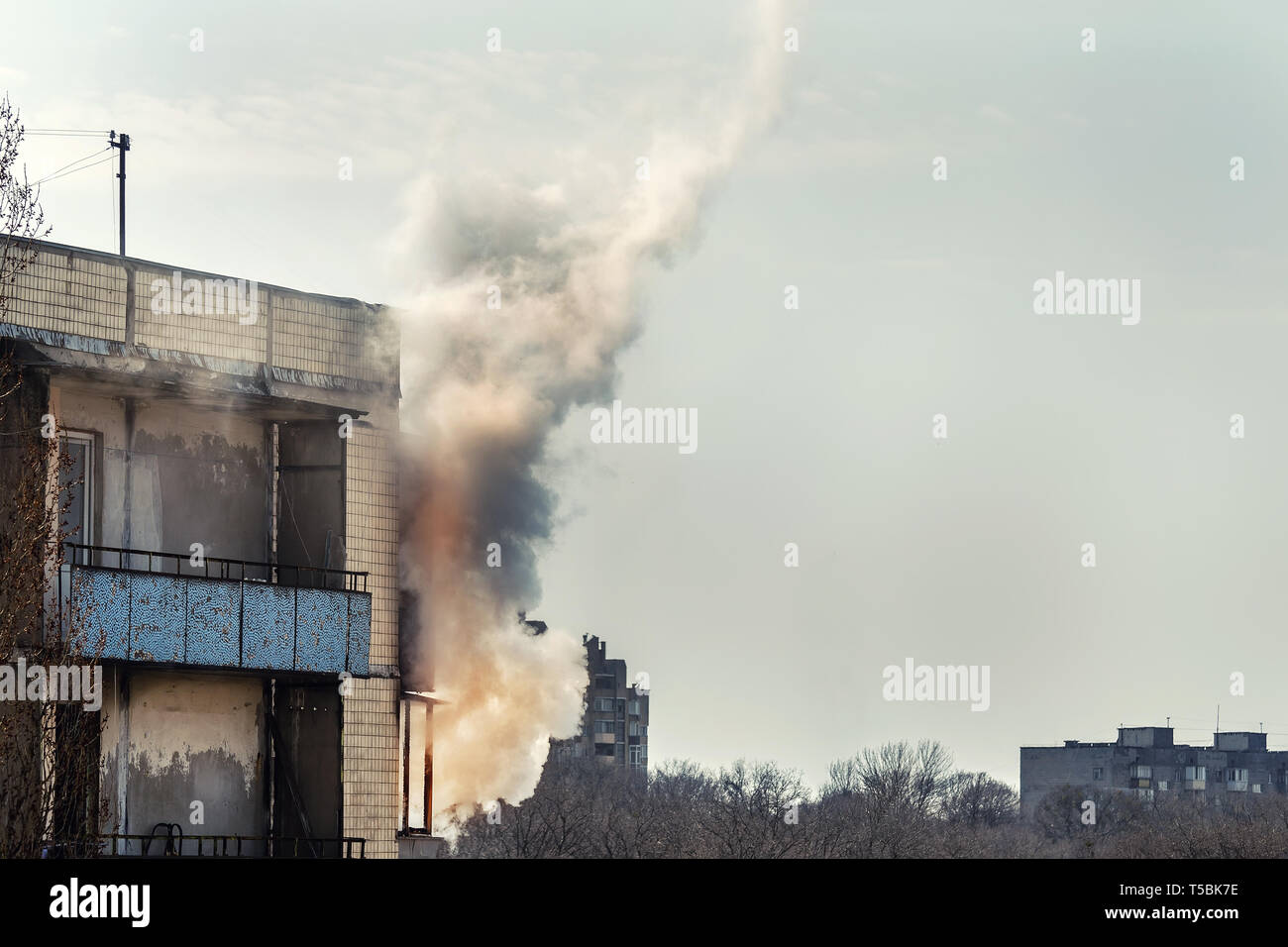 Il fuoco sul piano superiore del vecchio edificio di appartamenti. Nuvole di fumo curling dal balcone. usura cablaggio electic sulla casa di età e di corto circuito come contatto cas Foto Stock