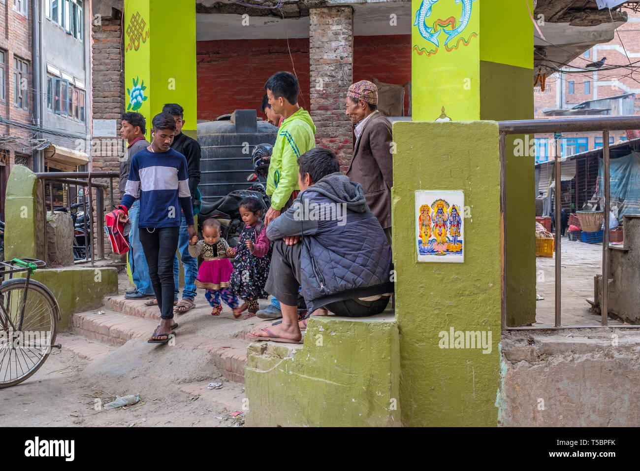 LALITPUR, PATAN NEPAL - Aprile 3, 2019: un papà nepalese con i suoi due bambini e altri uomini vicino a una scuola Foto Stock