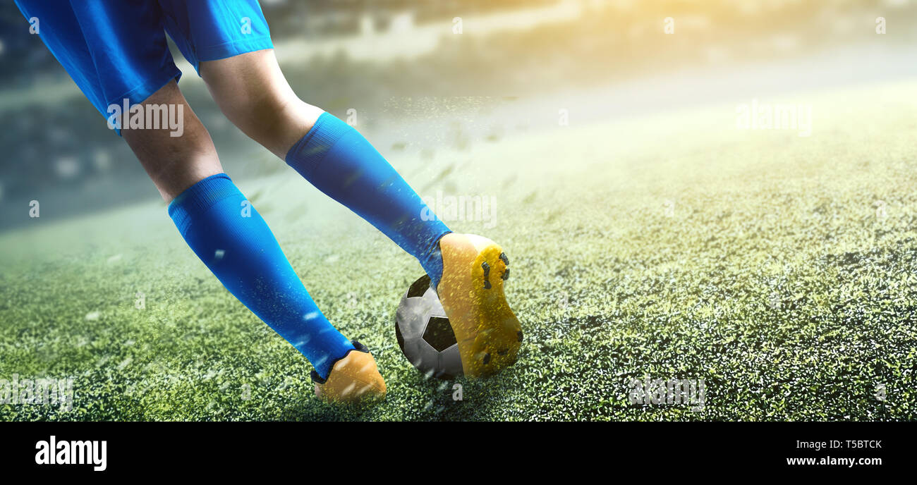 Vista posteriore del giocatore di football uomo calciare la palla sul campo di calcio a Stadium Foto Stock