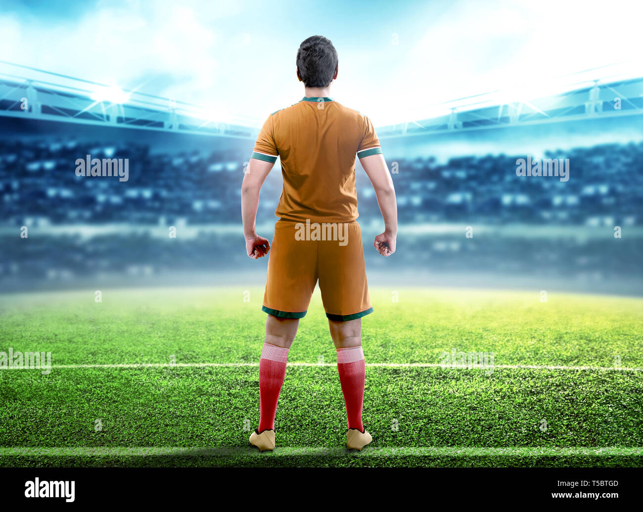 Vista posteriore del giocatore di football uomo in piedi al centro del campo di calcio di Stadium Foto Stock