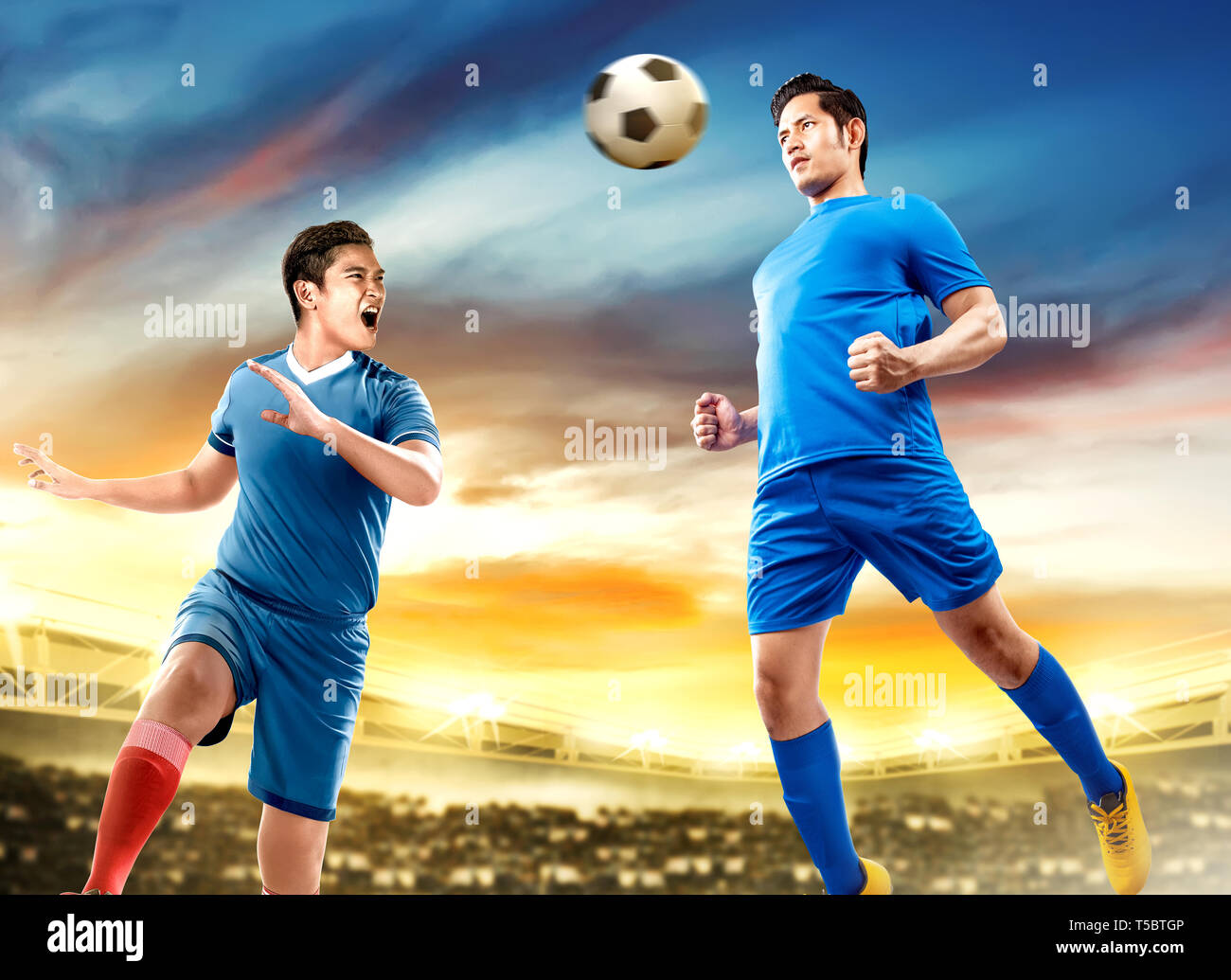 Due asian giocatore di football uomo saltare in aria e il duello voce la palla sul campo di calcio a Stadium Foto Stock