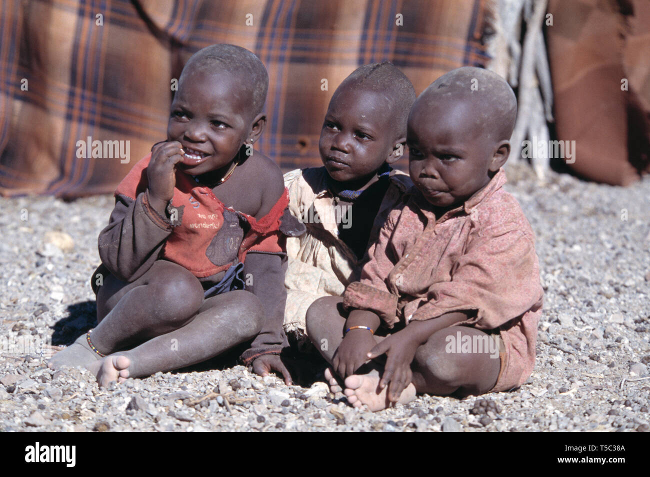 La Namibia. Tribù Himba village. Bambini seduti fuori. Foto Stock
