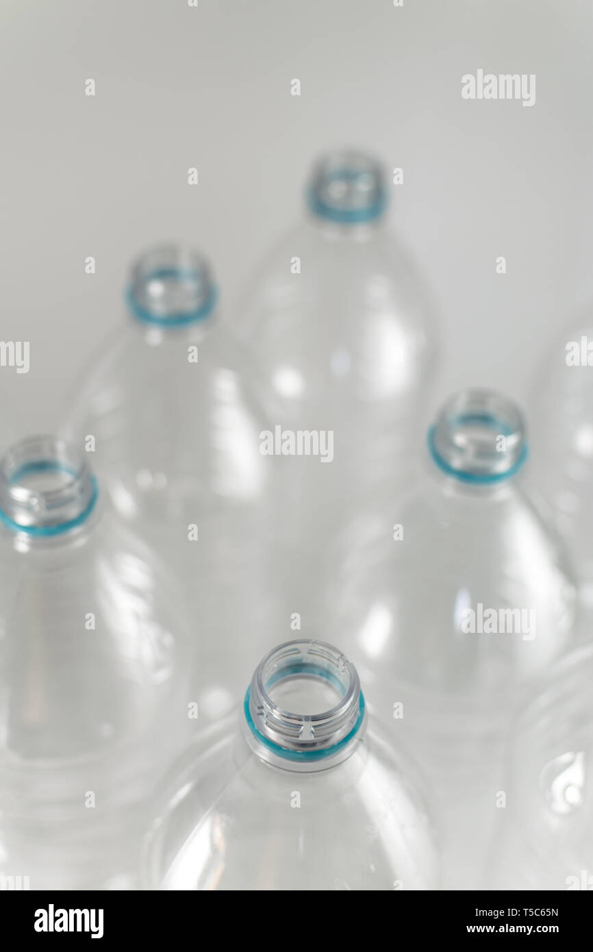 I colli di bottiglia di un pacco di litro e mezzo di vuoto di acqua minerale senza tappi con il solo blu anello di tenuta su uno sfondo bianco. Il riutilizzo Eco-Friend Foto Stock