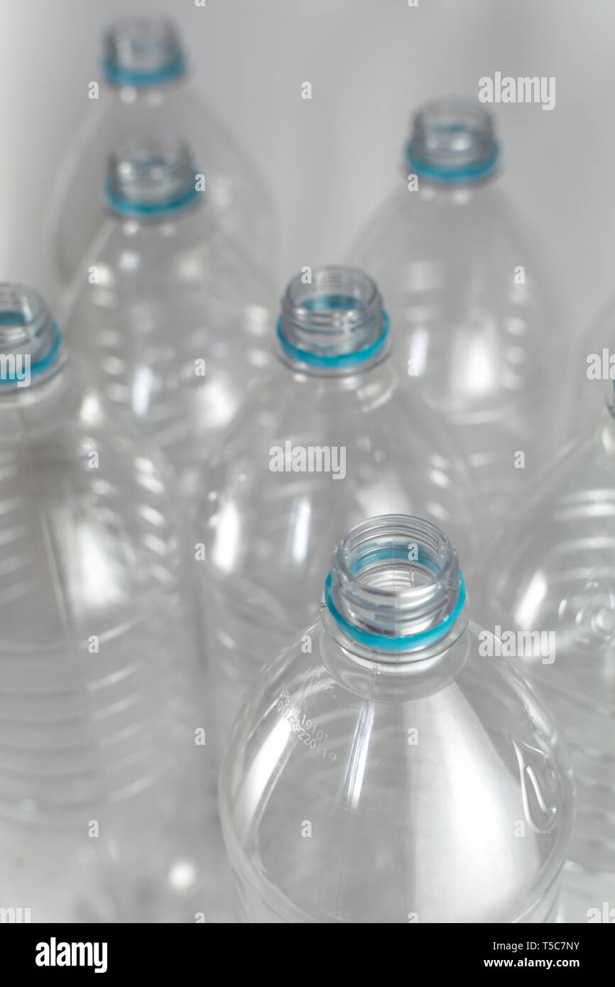 I colli di bottiglia di un pacco di litro e mezzo di vuoto di acqua minerale senza tappi con il solo blu anello di tenuta su uno sfondo bianco. Il riutilizzo eco Foto Stock