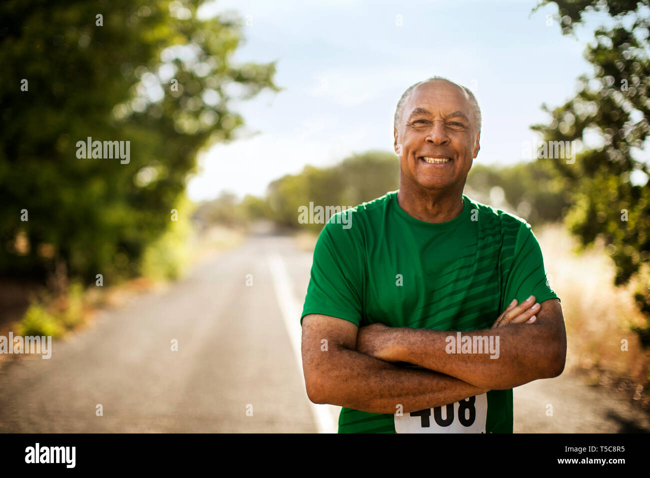 Ritratto di un sorridente uomo maturo jogging su una strada rurale. Foto Stock