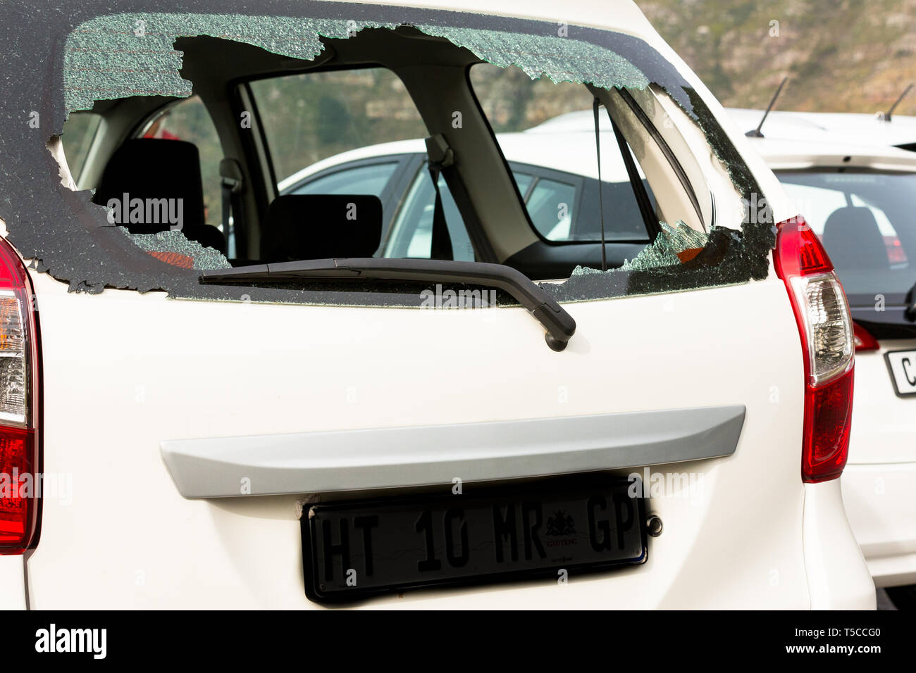 O posteriore vista posteriore della vettura bianca e infranto il vetro di una finestra a causa di criminalità, furto, furto, atti di vandalismo in una zona urbana di Città del Capo, Sud Africa Foto Stock