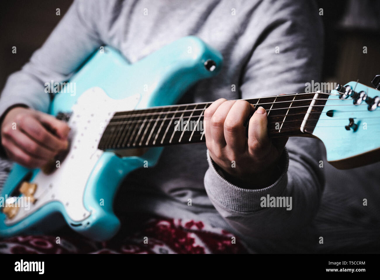 Donna blu di suonare una chitarra elettrica vicino a casa. La pratica di chitarra e giocare da solo Foto Stock
