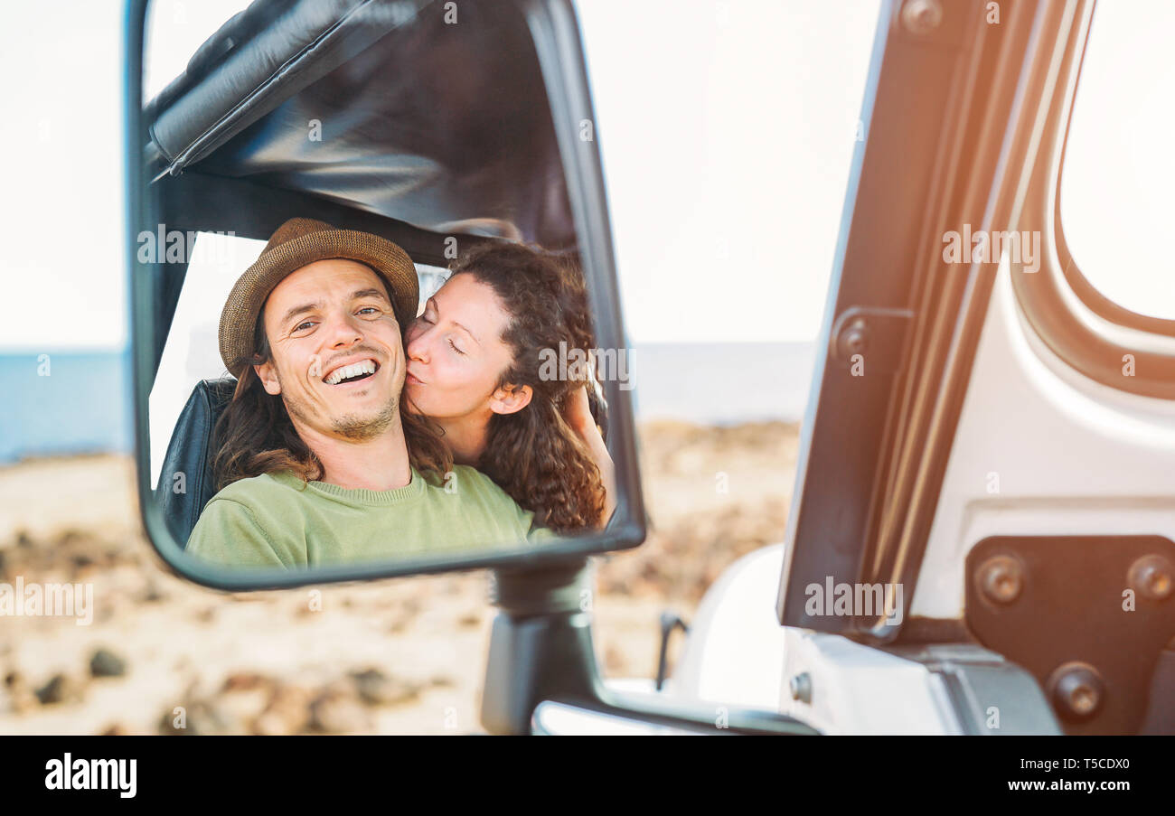 Felice coppia avente un momento di gara durante il loro viaggio con una vettura convertibile - Pov in uno specchio auto di giovani persone di viaggio nella loro vacanza Foto Stock