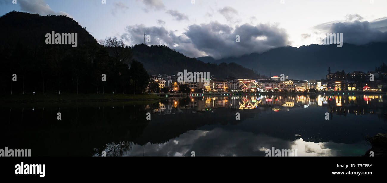 La città di notte vista del paesaggio di montagna e di sfondo cielo nuvoloso riflessione sull acqua situato a SAPA, Vietnam. Il lago nel centro di Sapa. panorama Foto Stock