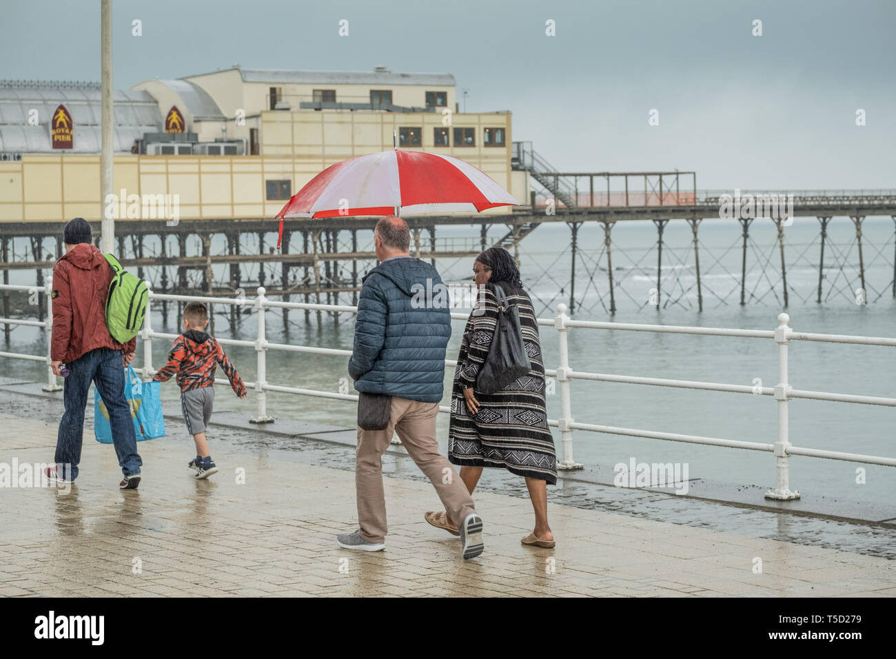 Aberystwyth, UK. 24 apr, 2019. Regno Unito . Regno Unito: Meteo dopo la faceva un caldo tremendo e il record di tempo oltre le vacanze di Pasqua, il meteo ha restituito alla sua stagione la norma con il grigio delle nubi e pioggia battente verso il basso le poche persone camminando lungo il lungomare in Aberystwyth sulla West Wales coast Photo credit: keith morris/Alamy Live News Foto Stock