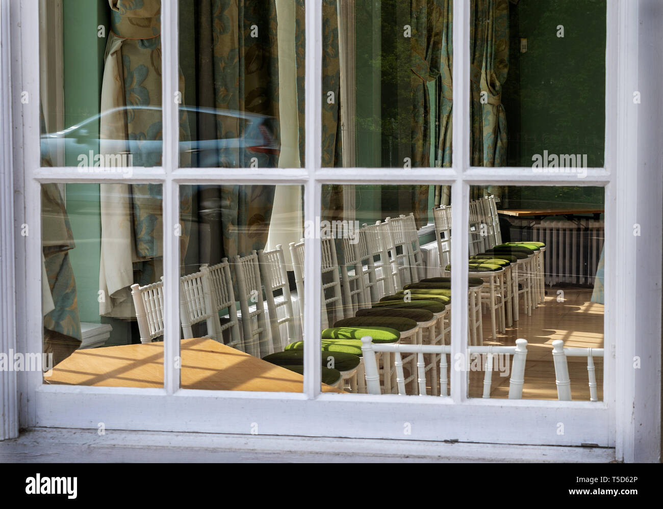 Una vista attraverso una finestra nel gruppo di camere in Royal Lemington Spa mostra sedie vuote con un atmosfera di tristezza Foto Stock