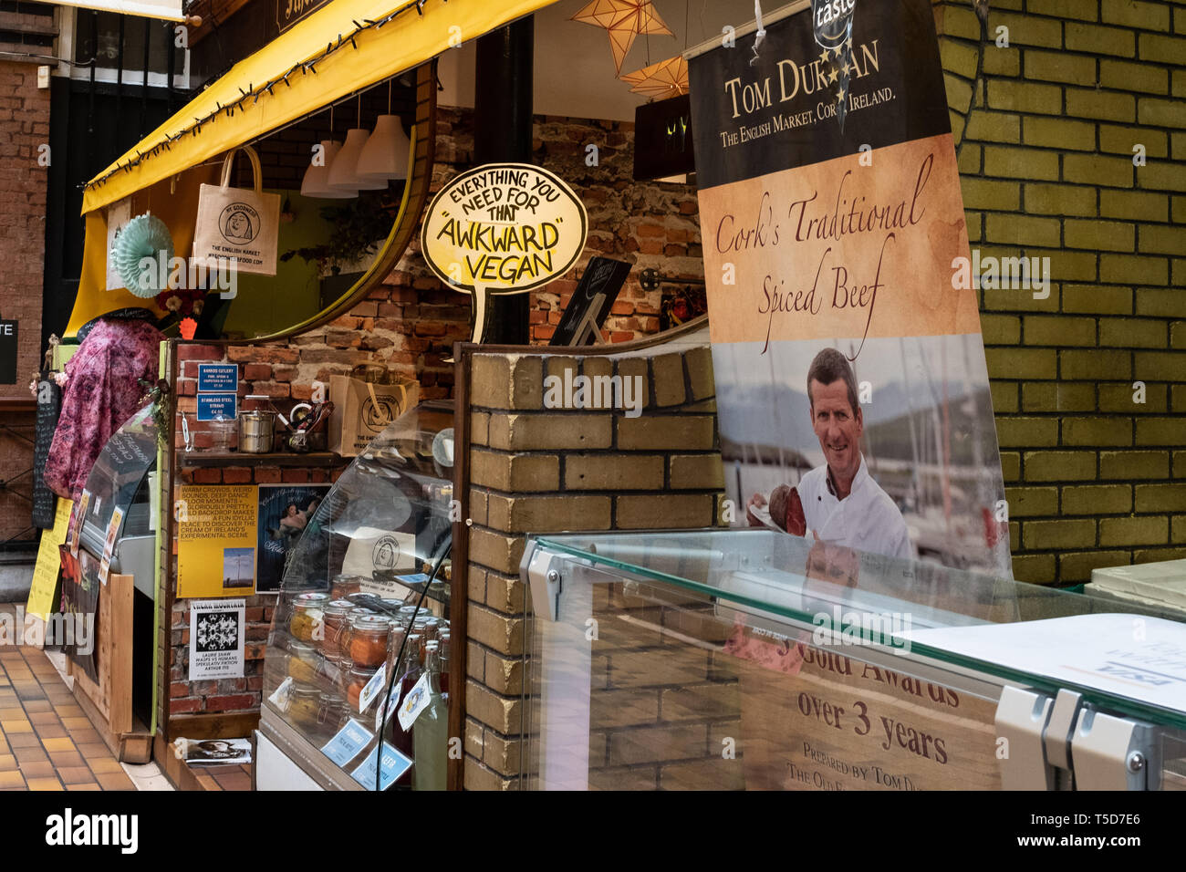 Stallo vegana e commerciante di carne al mercato inglese, Cork, Irlanda Foto Stock