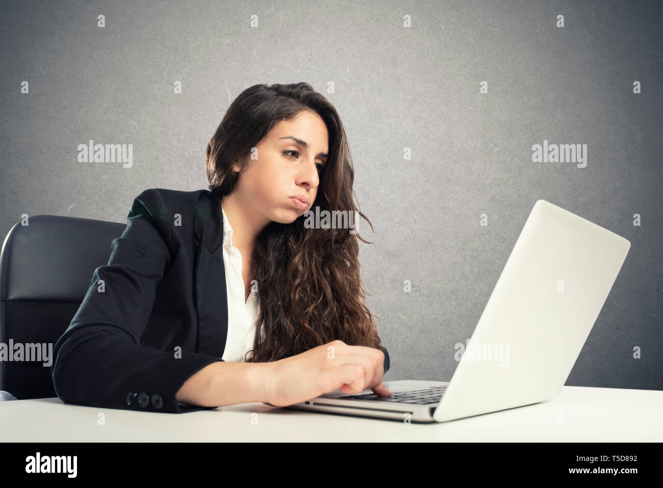 Annoiato donna snorts in ufficio mentre si lavora sul computer portatile Foto Stock